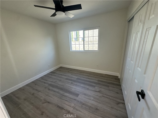 unfurnished bedroom with ceiling fan, dark wood-type flooring, and a closet