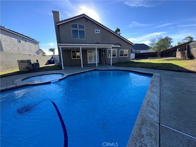 view of pool with a patio area, a yard, and an in ground hot tub