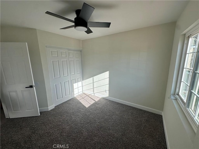 unfurnished bedroom featuring a closet, dark carpet, and ceiling fan