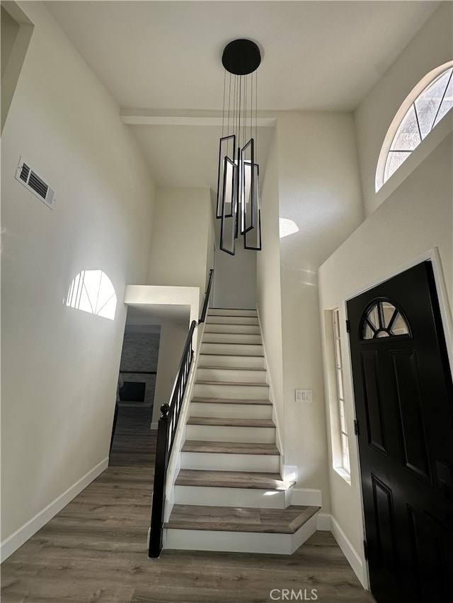 entrance foyer with hardwood / wood-style floors, a notable chandelier, and beam ceiling