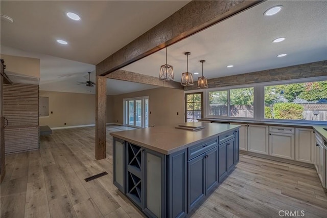 kitchen featuring white cabinetry, a center island, blue cabinets, decorative light fixtures, and light wood-type flooring