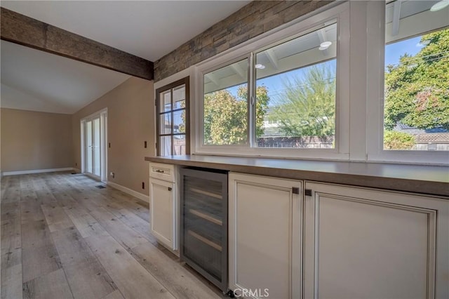 kitchen featuring light wood-type flooring, white cabinetry, plenty of natural light, and beverage cooler