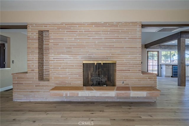 details featuring hardwood / wood-style floors, beverage cooler, and a brick fireplace