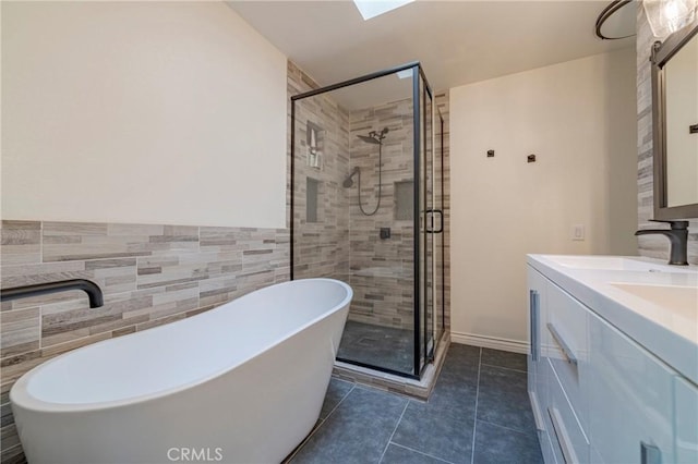 bathroom with a skylight, tile patterned floors, vanity, tile walls, and shower with separate bathtub