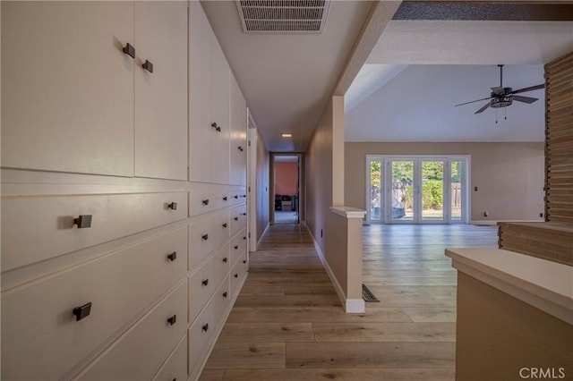 corridor featuring french doors, light wood-type flooring, and lofted ceiling