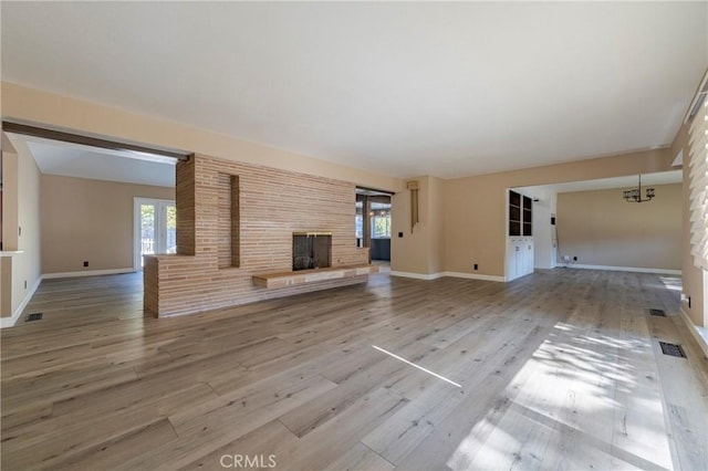 unfurnished living room featuring a fireplace, a chandelier, and hardwood / wood-style flooring