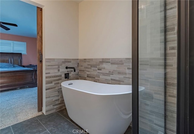 bathroom featuring tile patterned flooring, tile walls, a tub, and ceiling fan