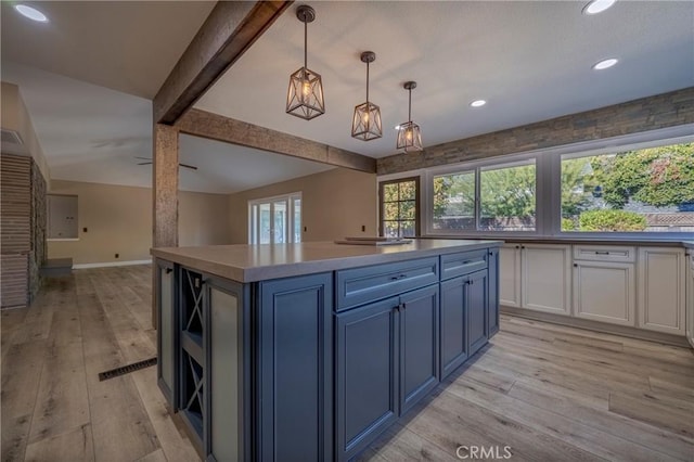 kitchen with a center island, blue cabinets, light hardwood / wood-style flooring, decorative light fixtures, and white cabinetry