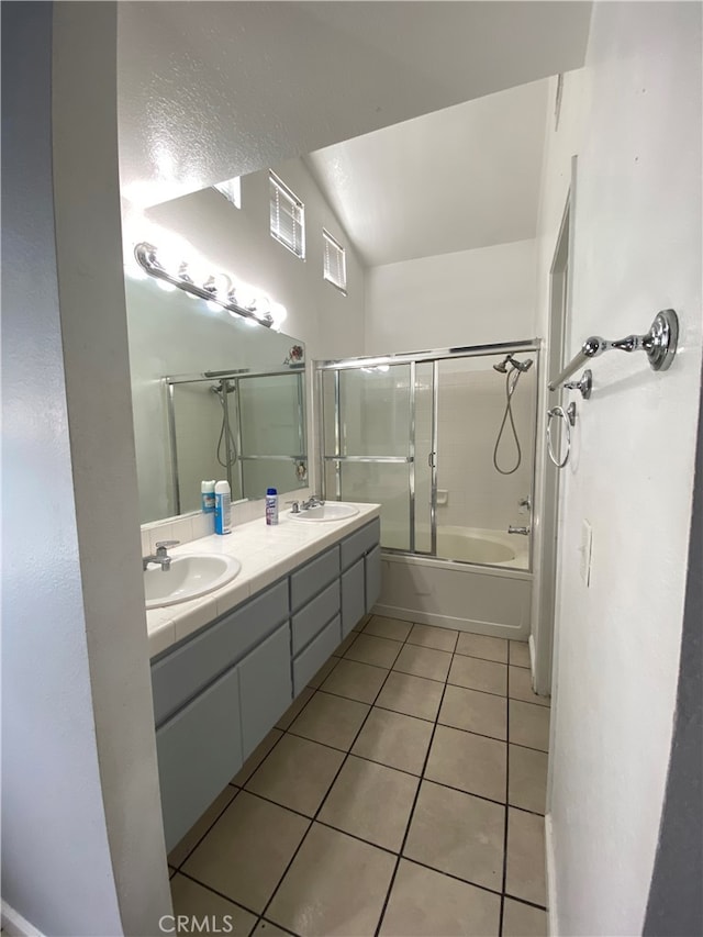 bathroom with tile patterned flooring, vanity, bath / shower combo with glass door, and vaulted ceiling