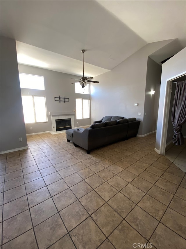 tiled living room featuring plenty of natural light, ceiling fan, lofted ceiling, and a tiled fireplace