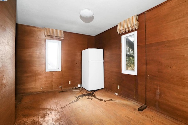 unfurnished room featuring a wealth of natural light, wooden walls, and hardwood / wood-style flooring