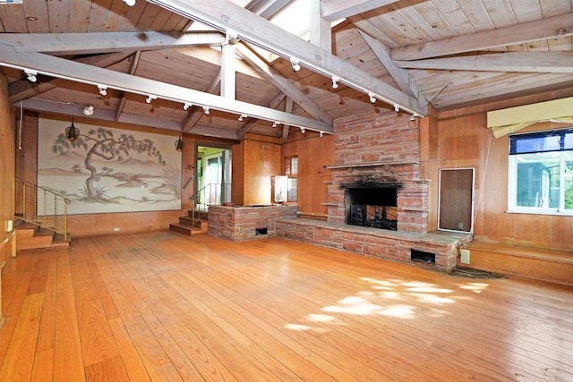 unfurnished living room with lofted ceiling with beams, wood walls, hardwood / wood-style floors, a fireplace, and wood ceiling