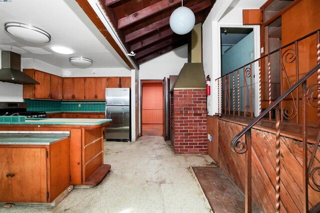 kitchen with stainless steel refrigerator, wall chimney exhaust hood, black gas range oven, tasteful backsplash, and decorative light fixtures