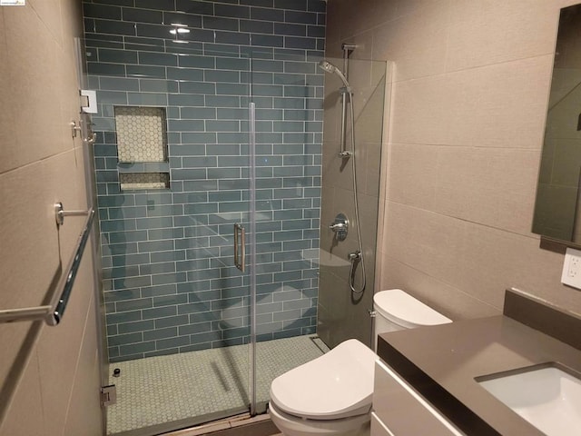 bathroom featuring vanity, a shower with shower door, tile walls, and toilet