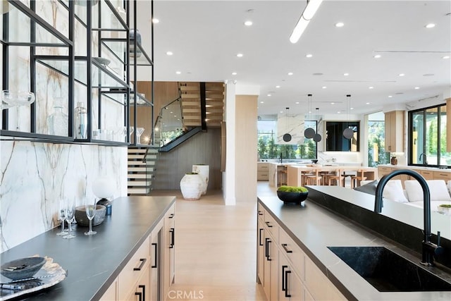 kitchen with light hardwood / wood-style floors, sink, and hanging light fixtures