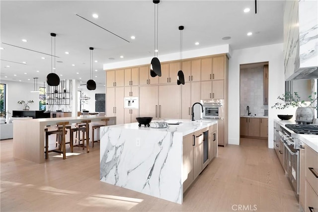 kitchen with light brown cabinets, a spacious island, and hanging light fixtures