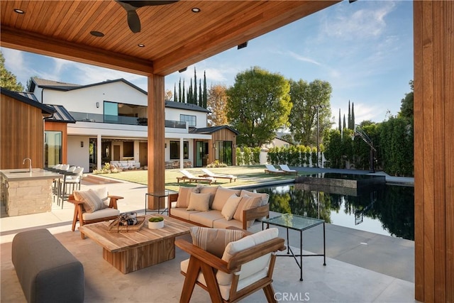 view of patio / terrace with ceiling fan, a water view, exterior bar, and an outdoor hangout area