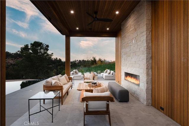 patio terrace at dusk featuring an outdoor living space with a fireplace and ceiling fan