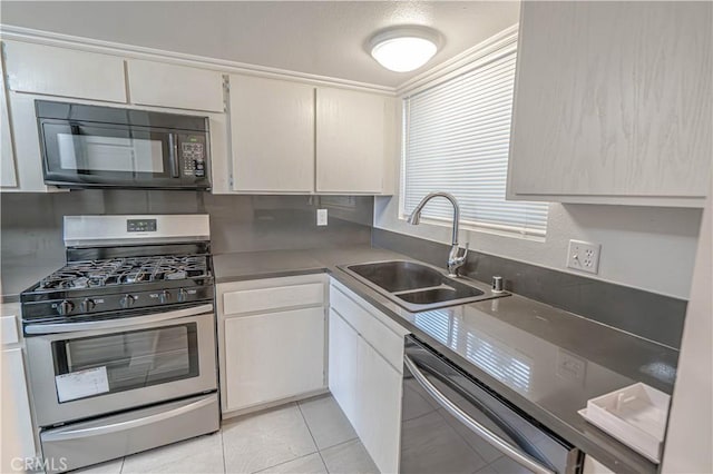 kitchen featuring white cabinets, sink, light tile patterned floors, and stainless steel appliances