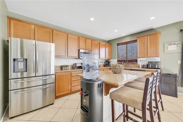 kitchen featuring a center island, sink, light tile patterned floors, light stone countertops, and appliances with stainless steel finishes