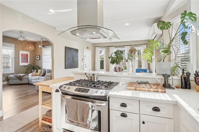 kitchen with ceiling fan, a healthy amount of sunlight, white cabinetry, and stainless steel gas range