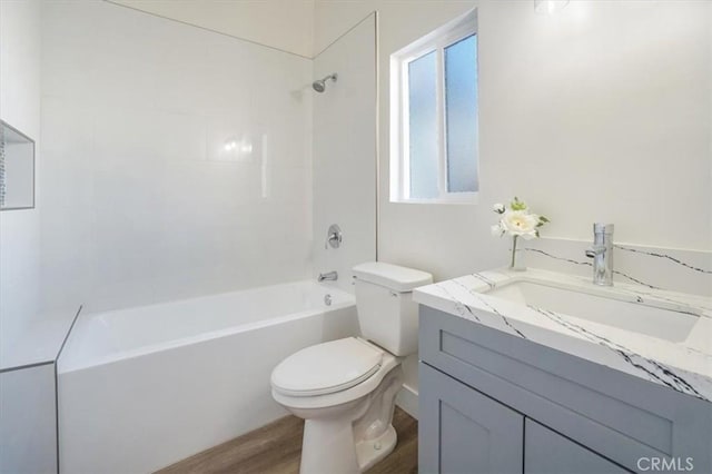 full bathroom with hardwood / wood-style floors, vanity, tiled shower / bath combo, and toilet