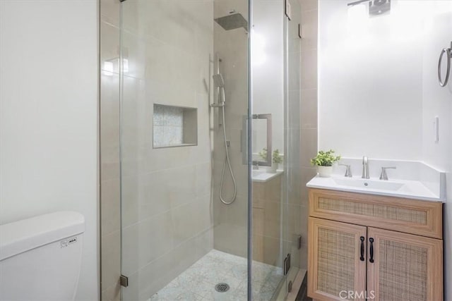 bathroom featuring vanity, a shower with shower door, and toilet