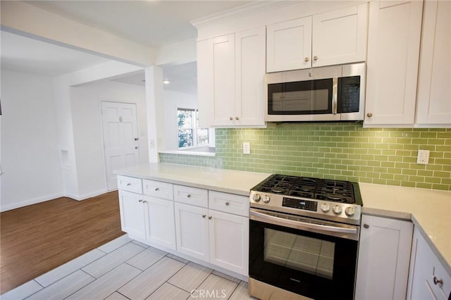 kitchen featuring white cabinets, light wood-type flooring, stainless steel appliances, and tasteful backsplash