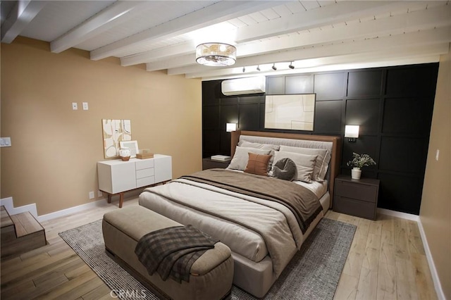 bedroom with beam ceiling, light hardwood / wood-style floors, and a wall mounted AC