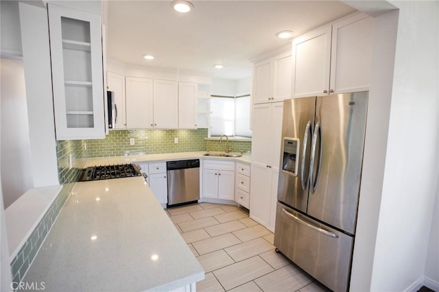 kitchen featuring backsplash, white cabinets, sink, light stone countertops, and appliances with stainless steel finishes