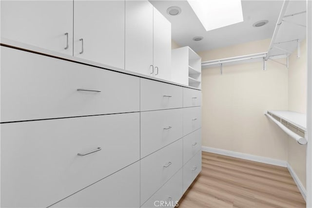 walk in closet featuring light wood-type flooring and a skylight