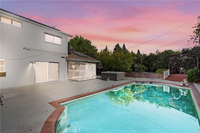 pool at dusk with central AC, a patio, and a hot tub