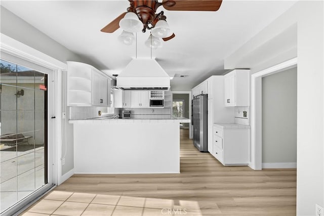 kitchen with appliances with stainless steel finishes, light hardwood / wood-style flooring, white cabinetry, and a wealth of natural light