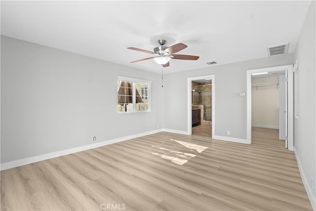 unfurnished bedroom with a walk in closet, ceiling fan, a closet, and light hardwood / wood-style floors