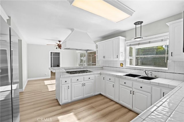 kitchen featuring tile countertops, custom exhaust hood, white cabinets, and sink