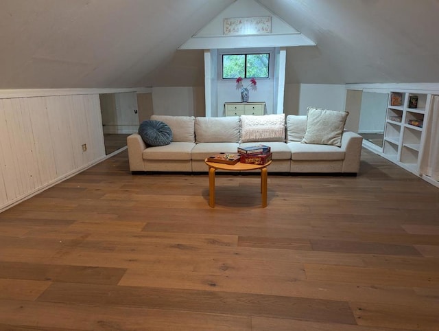 living area featuring hardwood / wood-style flooring, lofted ceiling, and wooden walls