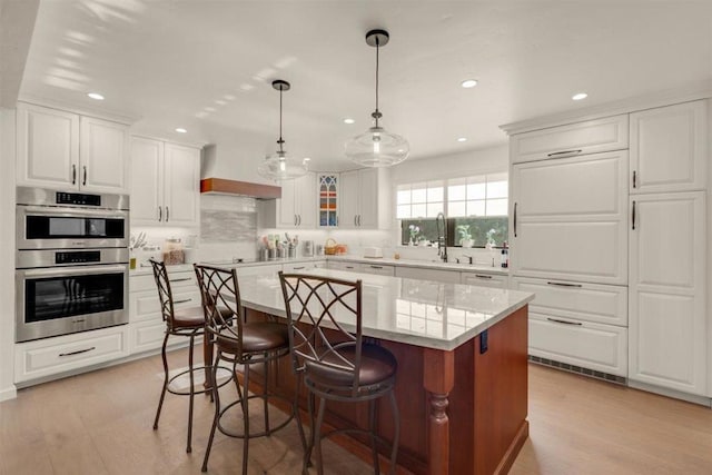 kitchen with white cabinetry, sink, a center island, and stainless steel double oven