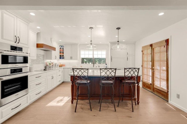 kitchen with white cabinetry, decorative light fixtures, tasteful backsplash, and light wood-type flooring