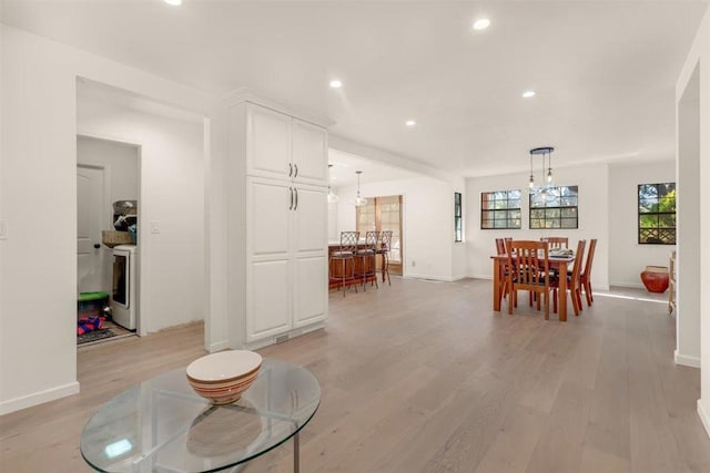 dining area with washer / dryer, light hardwood / wood-style flooring, and a chandelier