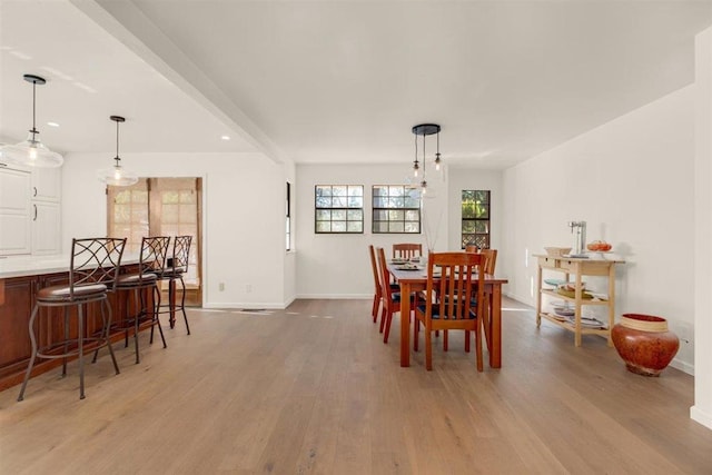 dining area with an inviting chandelier, beam ceiling, and light hardwood / wood-style floors