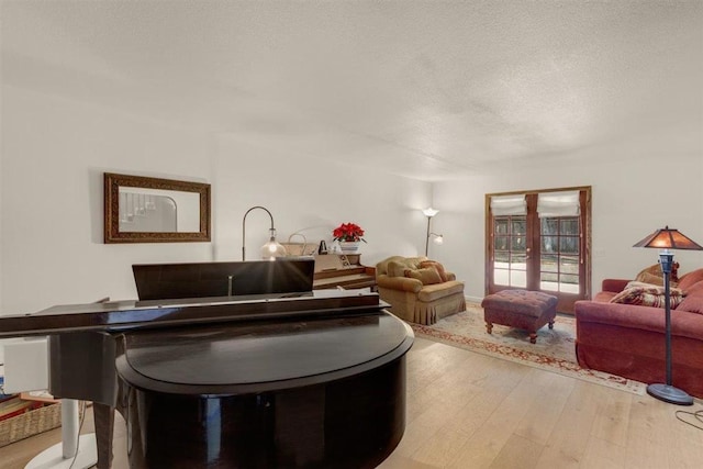 living room featuring french doors, light hardwood / wood-style flooring, and a textured ceiling