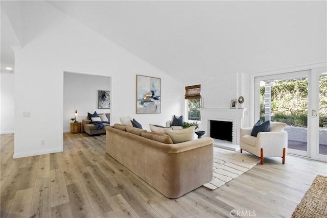 living room featuring plenty of natural light, light wood-type flooring, and high vaulted ceiling