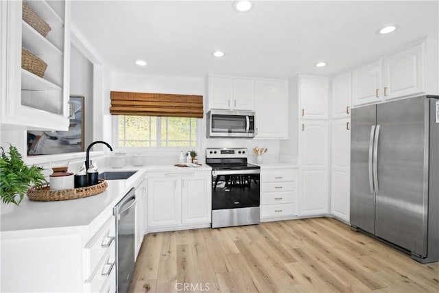 kitchen featuring appliances with stainless steel finishes, light hardwood / wood-style floors, white cabinetry, and sink