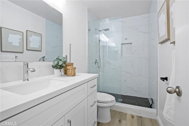 bathroom featuring hardwood / wood-style flooring, vanity, toilet, and a tile shower