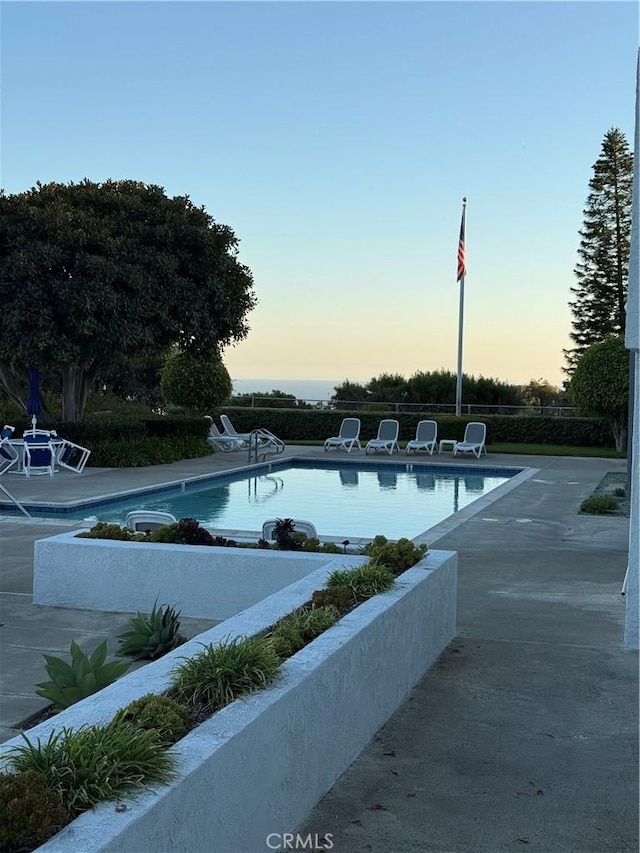 pool at dusk featuring a patio