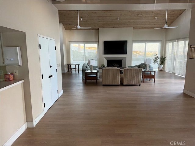 living room featuring plenty of natural light, ceiling fan, dark hardwood / wood-style flooring, and a towering ceiling