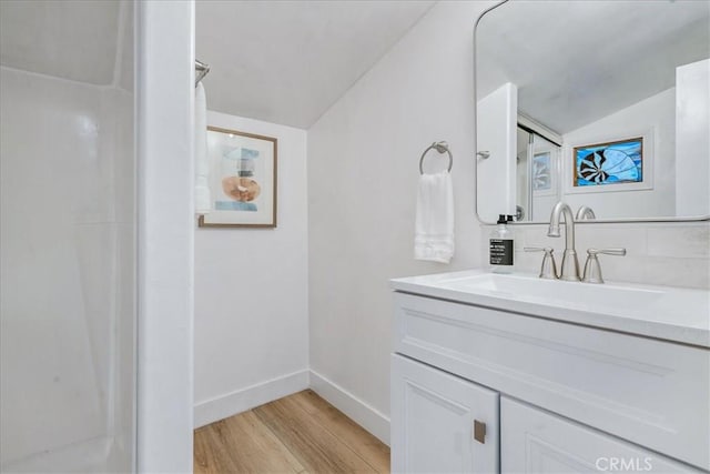 bathroom with lofted ceiling, vanity, wood-type flooring, and walk in shower