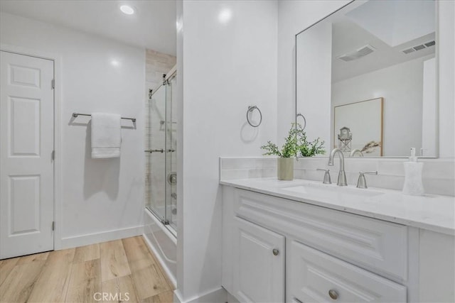 bathroom featuring wood-type flooring, enclosed tub / shower combo, and vanity