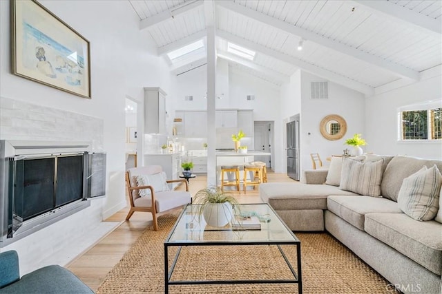 living room with light hardwood / wood-style floors, high vaulted ceiling, and beamed ceiling