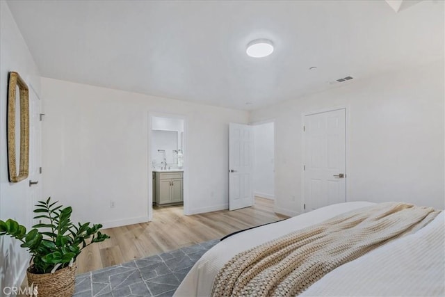 bedroom featuring ensuite bathroom and light hardwood / wood-style flooring